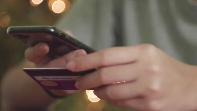 hands holding cell phone and credit card